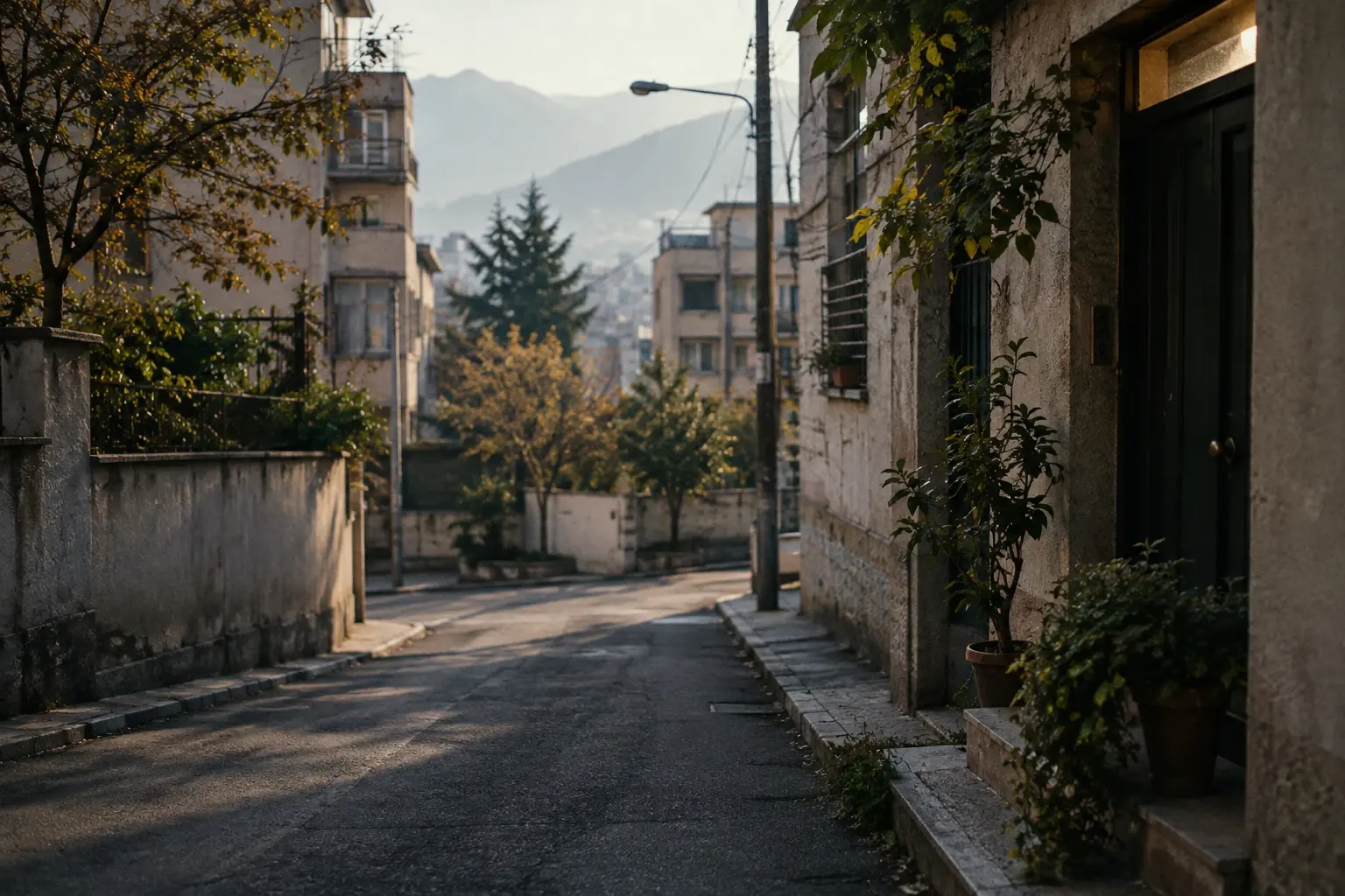 Rue résidentielle iranienne baignée de lumière, avec une porte entrouverte et des façades sobres, sans personne.